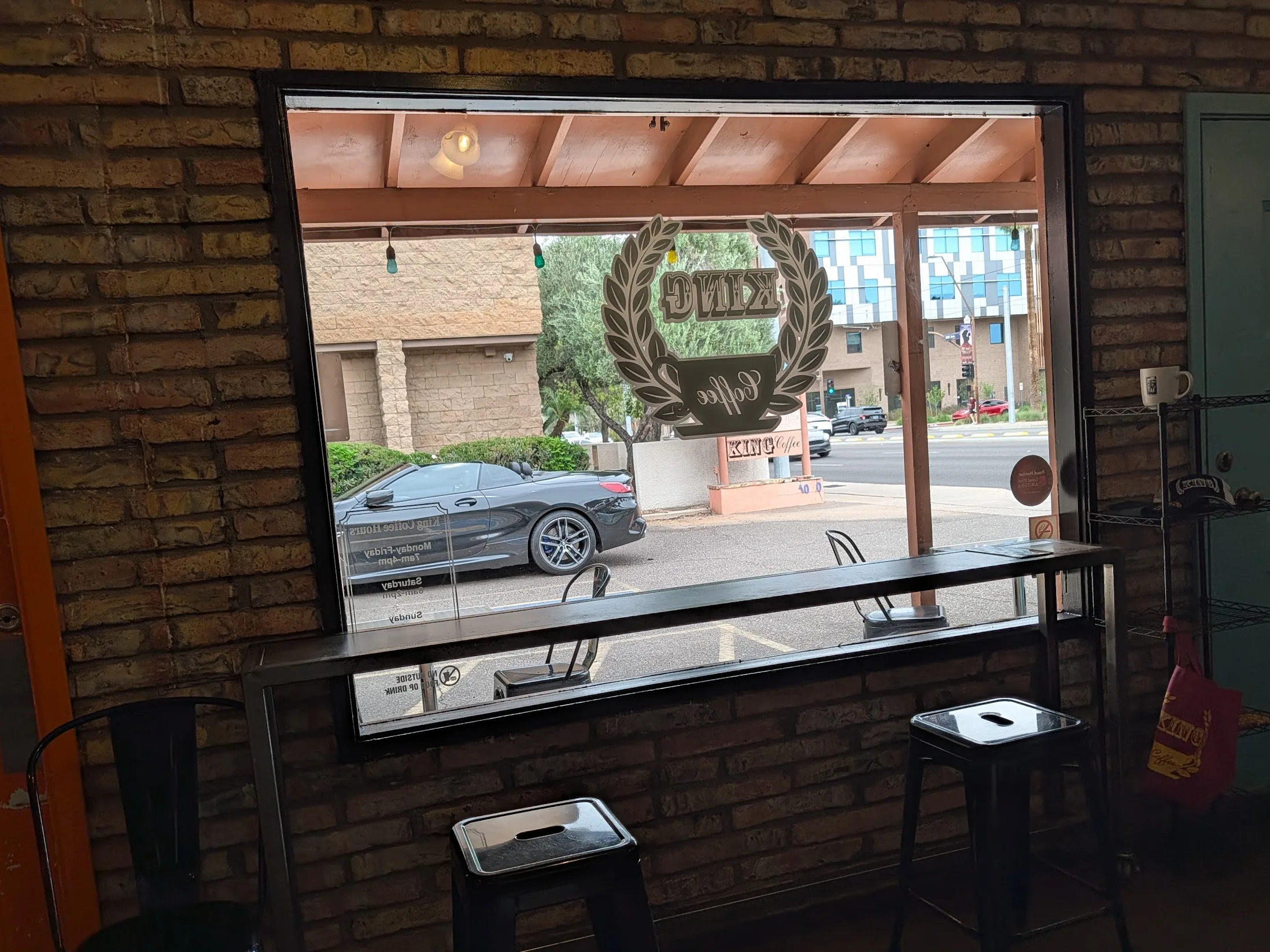 King Coffee Temp AZ. Image showing the large window inside the shop facing the parking and street. Bar stools and table are visible.